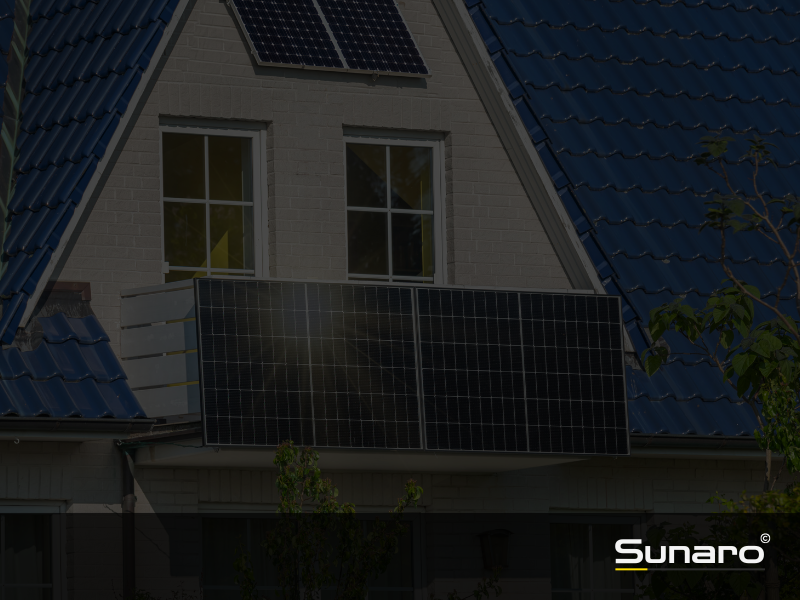 Haus mit blauer Dacheindeckung, Balkonkraftwerk und zusätzlichem Solarpanel auf dem Dach