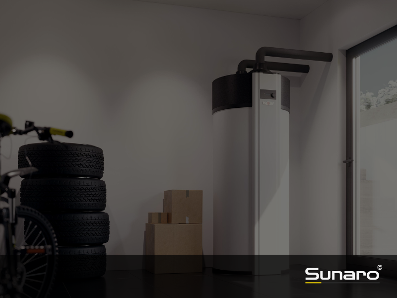 Warmwasserspeicher mit Wärmepumpenfunktion in modernem Hauswirtschaftsraum neben Reifen und Kartons